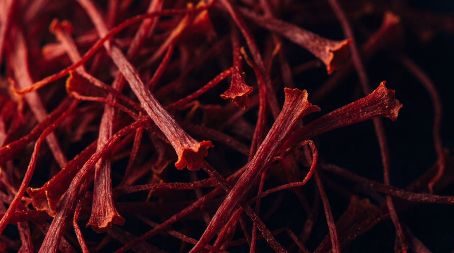 Extreme close-up of dried crimson saffron threads massed together against a near-black background